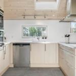 Modern kitchen with stainless steel appliances, wooden ceiling, and window view.