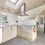 Kitchen with wooden ceiling, window, sink, range hood, and stove.