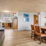 Ein Raum mit Essbereich, Küchenzeile und grünem Sofa. Holzdecke und Boden.