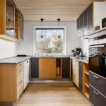 Küche mit Holz- und Schrankfronten, Fenster, Spüle und Einbauküchengeräten.