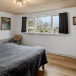 Schlafzimmer mit Bett, Fenster und Holzboden. An der Wand hängen Bilder.