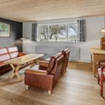 Wohnzimmer mit Ledersofa, Holztisch und Blick auf Felder.