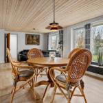 Esszimmer mit Rattan-Stühlen und Holztisch. Große Fenster und Holzdecke.