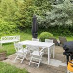 Hinterhof mit weißem Tisch, Stühlen, Bank, Grill und Sonnenliegen.