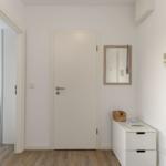 Flur mit Tür, Spiegel und Schrank. Im Hintergrund ist ein Schlafzimmer sichtbar.