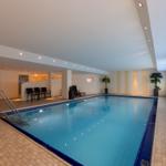 Innenpool mit Sauna, Liegestühlen und Pflanzen an den Wänden.