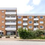 Modernes Mehrfamilienhaus mit Balkonen und Geschäften im Erdgeschoss.