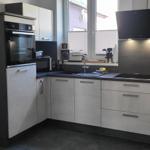 Moderne Küche mit Edelstahlspüle und integriertem Backofen.