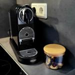 Kaffeemaschine mit Kapseln auf Küchenarbeitsplatte neben Induktionskochfeld.