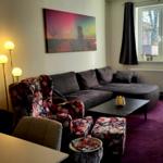 Wohnzimmer mit Sofa, Sessel und Teppich. Fenster und Tür bieten Licht.