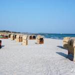 Beach with beach chairs, sand, and sea under blue sky