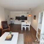 Apartment with dining area, kitchen, and living area with brown sofa and brown armchair.
