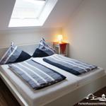 Bedroom with sloped ceiling, skylight, bed, and two nightstands with lamps.