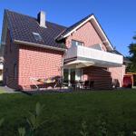Red brick house with balcony, terrace, and garden. Hammock seating area.