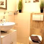 Badezimmer mit Waschbecken, Toilette und Pflanzen an der Wand.