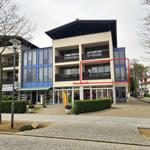 Ferienwohnung mit Balkon und großen Fenstern im modernen Gebäude.