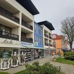 Strandnahe Geschäfte mit Schuhgeschäft und Irish Pub. Mehrstöckige Gebäude mit Balkonen.