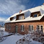 Haus mit Schneedecke, rotem Backstein und Dachgauben.