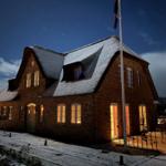 Schöne Villa mit Schneebedecktem Dach und erleuchteten Fenstern bei Nacht.