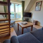 Wohnzimmer mit Sofa, Couchtisch und TV. Balkon mit Blick auf Grünflächen.