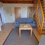 Wohnzimmer mit Sofa, Tisch und Holztreppe.