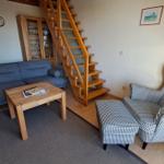 Wohnzimmer mit Sofa, Sessel und Holztreppe