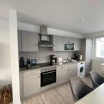 Modern kitchen with gray cabinets, cooktop, and washing machine.