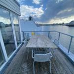 Deck with table and chairs by the water. View of harbor and buildings across the water.
