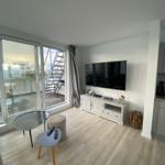 Living room with TV, terrace and wooden floor. Modern furniture and large windows.