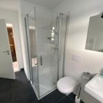 Bathroom with shower, toilet, and sink. Tile floor and mirror.