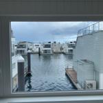 From the window, you can see a harbor with modern houses and water.