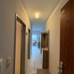 Flur mit Tür, Garderobe und Blick in Wohnzimmer mit Sessel.