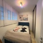 Schlafzimmer mit Bett, Wandbild und Fenster mit Vorhängen.