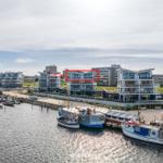 Modernes Apartmenthaus am Hafen mit Blick auf Wasser und Boote.