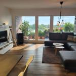 Wohnzimmer mit Sofa, TV und Balkon mit Pflanzen.