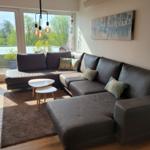 Ein Wohnzimmer mit einem großen Sofa, einem Tisch und einer Terrasse mit Blick auf Bäume.