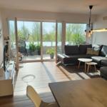 Wohnbereich mit Sofa, Tisch und Balkon mit Pflanzen.