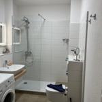 Badezimmer mit Dusche, Waschbecken, Toilette und Wärmeelement.