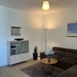 Wohnzimmer mit Sofa, Couchtisch, Fernseher und Glasvitrine.