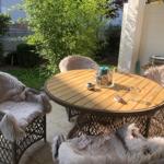Runder Holztisch mit vier Stühlen, bedeckt mit flauschigen Decken im Garten.