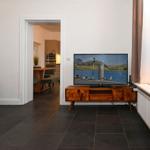 Wohnzimmer mit TV, Holzboard und Blick in die Küche.