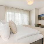 Doppelbett mit weißen Laken, Schreibtisch und TV an der Wand.