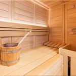 Sauna mit Holzbank, Eimer und Warnschild an der Wand.