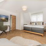 Schlafzimmer mit Bett, Schreibtisch, TV und Holzboden.