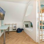 Kinderzimmer mit Kletterturm, Bett und Schreibtisch an der Wand.