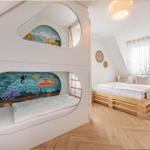 Zimmer mit Kinderbett und Doppelbett, Wandmalereien und Holzboden.