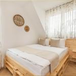 Schlafzimmer mit Holzbett, Fenster mit Vorhängen und Wanddekoration.