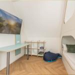 Ein Zimmer mit Schreibtisch, Regal und Schlafplatz in einem runden Kasten.