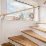 Treppe mit Holzgeländer und Fenster mit Blick auf Außenbereich.