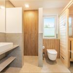 Badezimmer mit Waschbecken, Toilette und Sauna. Holz- und Steinoptik.